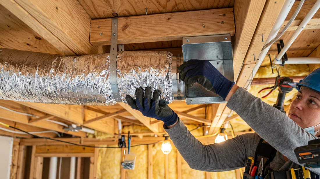 Technicien travaillant sur les gaines d'un système de climatisation en faux plafond